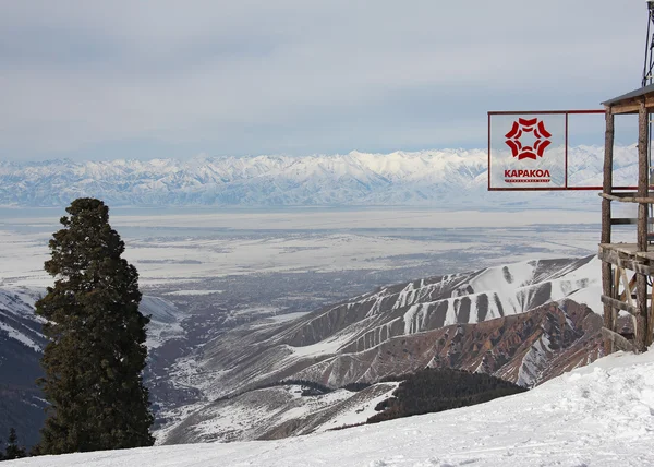 Sign of Karakol ski resort and view on the Issyk Kul lake — Stock Photo, Image