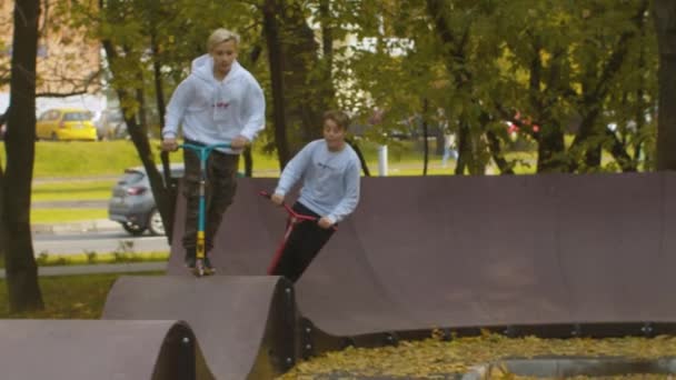 Хлопчики катаються на скутерах на трасі насоса — стокове відео
