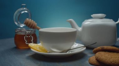 Çay demliği, çay fincanı, bal ve kurabiye.