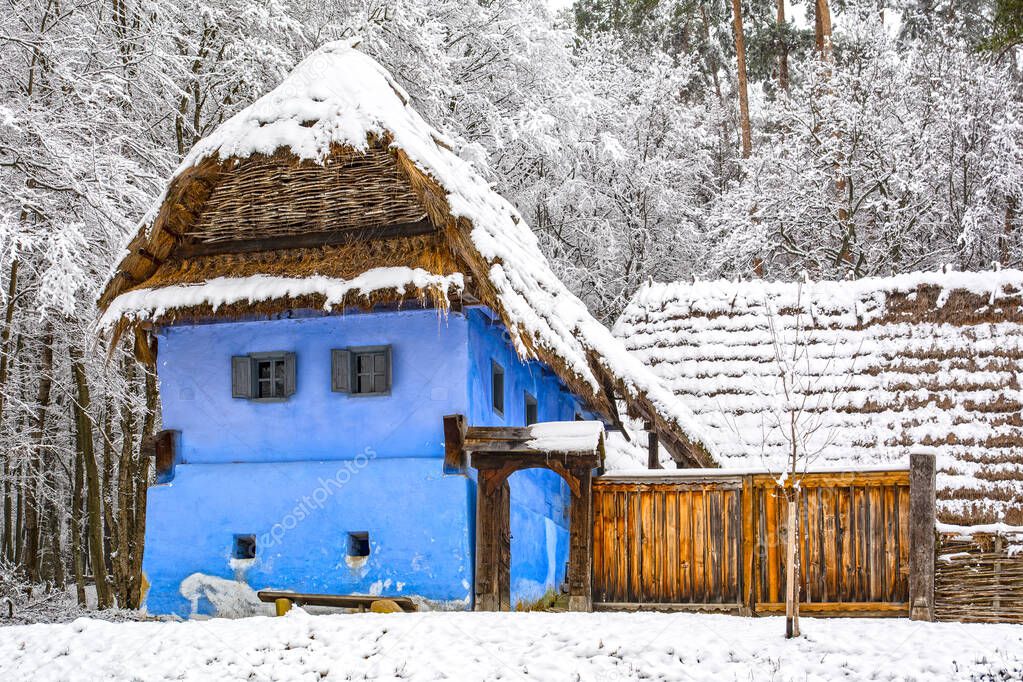 Beautiful traditional old blue house in Astra open air museum in Sibiu, Transylvania, during winter season with snow