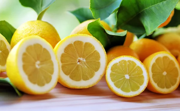 Zitronenscheiben auf Holztisch vor grünem Hintergrund — Stockfoto