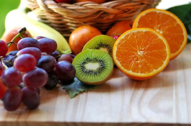 yarım portakal, dilimlenmiş kivi, masada diğer meyveler