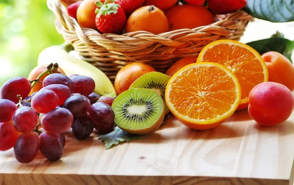 Media naranja, kiwi en rodajas, otras frutas en la canasta — Foto de Stock