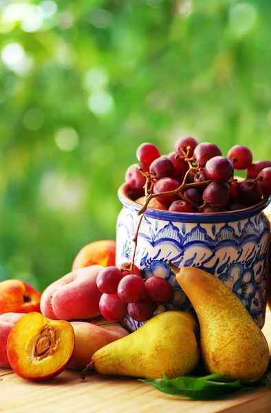 Pêssegos fatiados, peras e uvas em vaso cerâmico — Fotografia de Stock