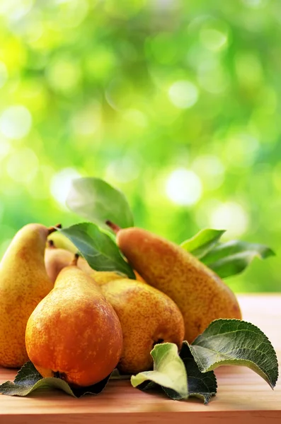 Rijpe peren en bladeren op tafel — Stockfoto