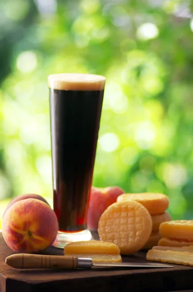 Formaggi stagionati, frutta e bicchiere di birra scura — Foto Stock