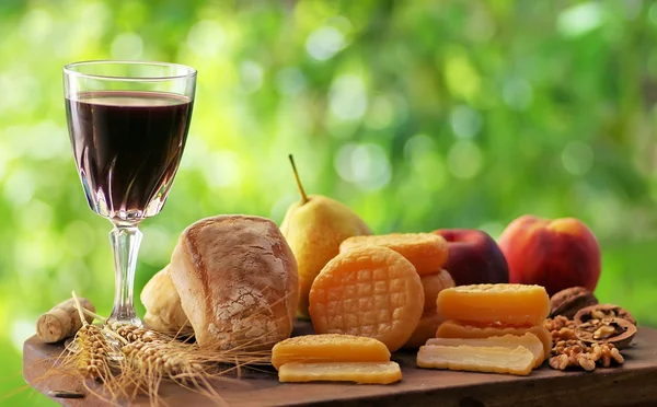 Cheese, bread, fruits and red wine on table — Stock Photo, Image