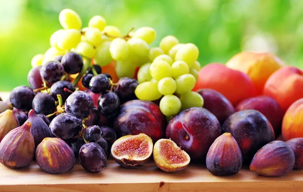 Fresh ripe fruits close-up: plums, peaches, figs and grapes — Stock Photo, Image