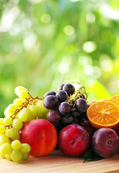 Sliced oranges, grappes, peaches and plums on table — Stock Photo, Image