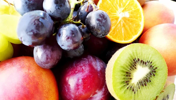 Laranjas e kiwis maduros cortados, uvas, pêssegos e ameixas — Fotografia de Stock