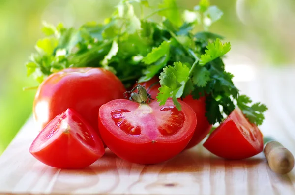 Rijpe tomaat, gesneden en koriander op tafel — Stockfoto