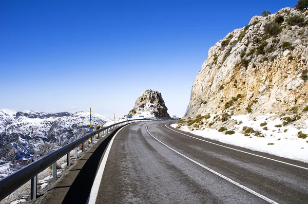 Camino de asfalto en pico de montaña con campos de nieve — Foto de Stock