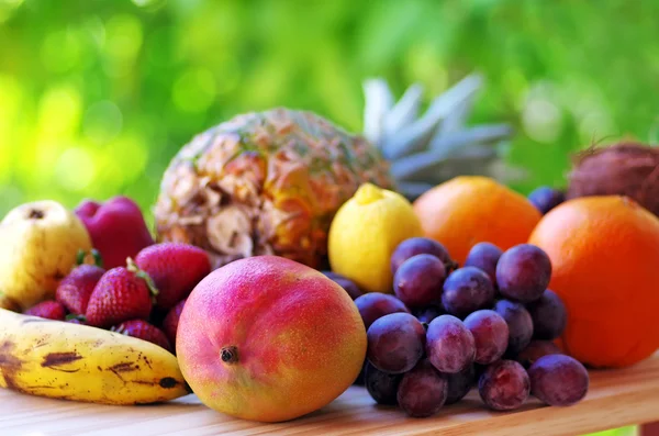 Assortimento di frutta su tavolo di legno su sfondo verde — Foto Stock