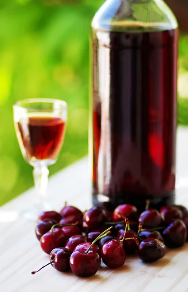 Cherry fruits and bottle of liqueur — Stock Photo, Image