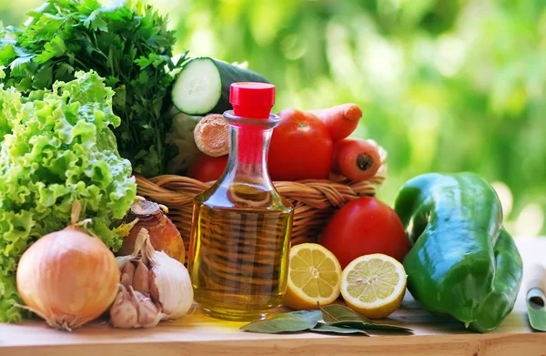 Оливковое масло и овощи на столе — стоковое фото