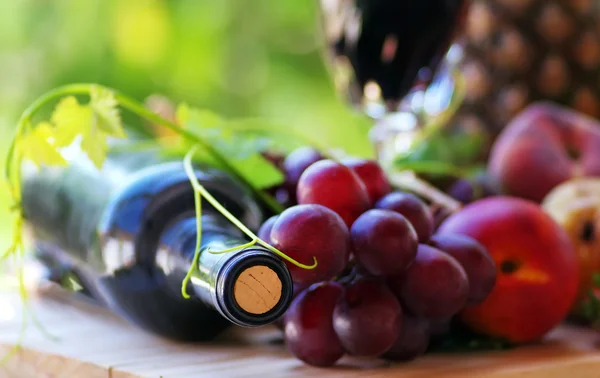 Botella de vino tinto y hojas de uva — Foto de Stock