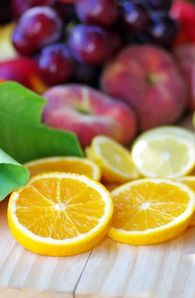 Naranja en rodajas y melocotones sobre mesa de madera — Foto de Stock