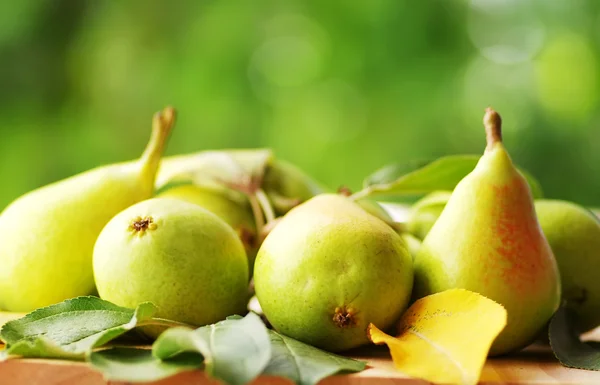 Päron med blad på trä bordet — Stockfoto