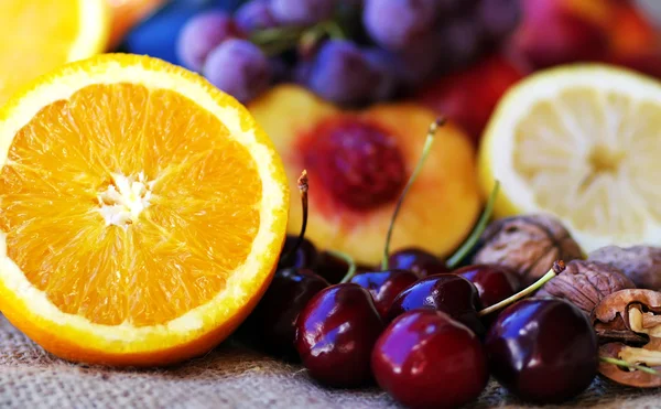 Plasterki pomarańczy i owoce na stole — Zdjęcie stockowe