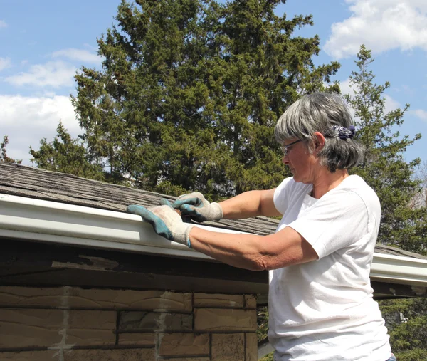 Woman spring cleaning rain gutters — Stock Photo, Image