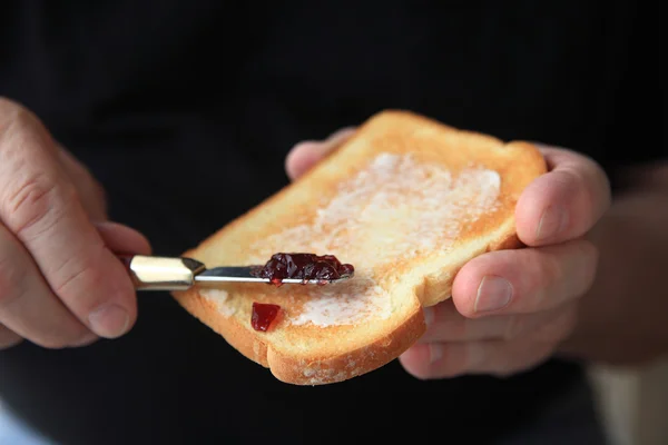Man prepares buttered toast with jam   — Stock fotografie
