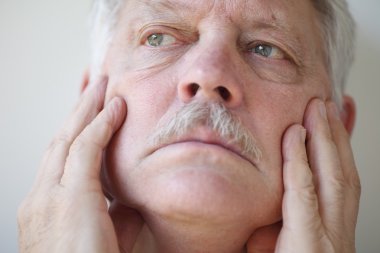 adam iki eliyle yüzünü dokunur