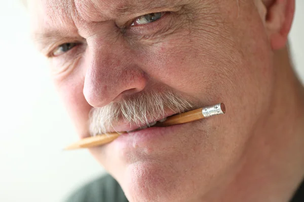 Homem mais velho com lápis entre os dentes — Fotografia de Stock