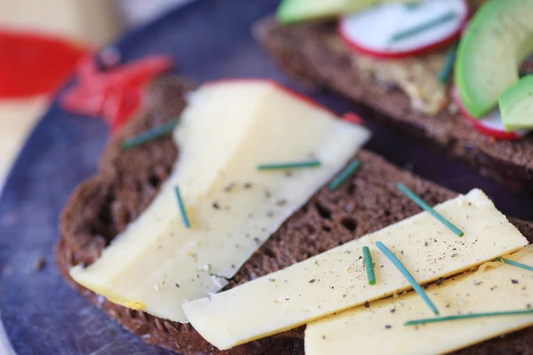 Sandwich de queso, aguacate y rábano sobre pan negro —  Fotos de Stock