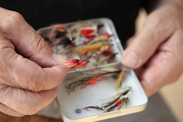 Homem com sua coleção de moscas de pesca artificiais — Fotografia de Stock