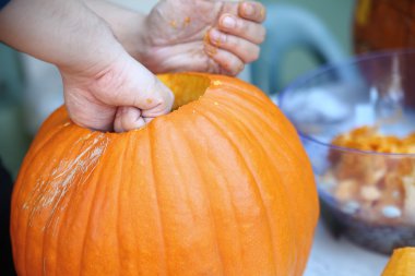 Man prepares Halloween pumpkin for carving clipart