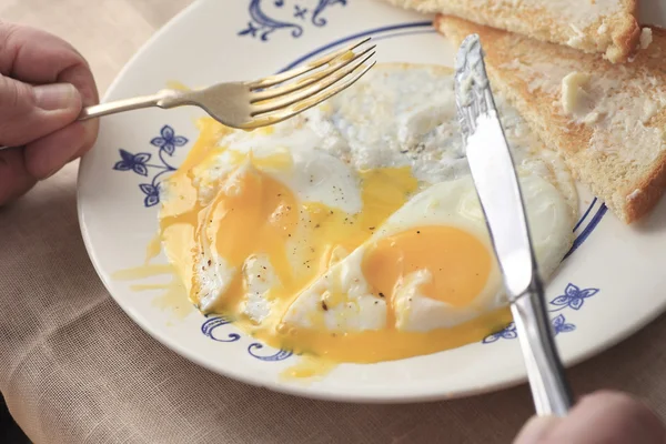 Äta rinnande stekt ägg och toast frukost — Stockfoto