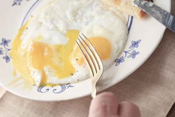Homem corta em seu pequeno-almoço ovos fritos — Fotografia de Stock