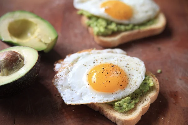 Två skivor av avokado rostat bröd med stekt ägg — Stockfoto