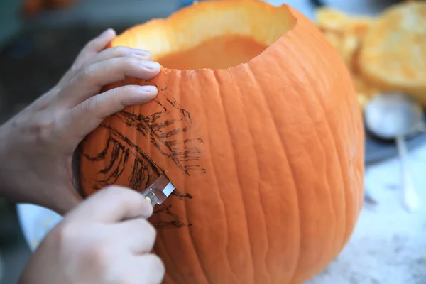 Человек использует парринг нож на Хэллоуин тыква — стоковое фото