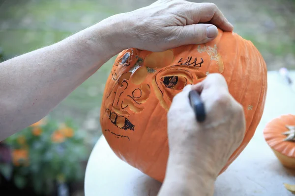 Мужчина работает над тыквой на Хэллоуин — стоковое фото