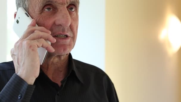 Senior man with white smartphone speaks — Stock Video