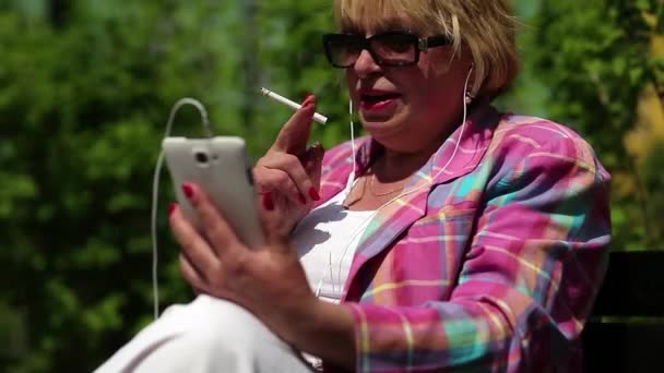 Vrouw met sigaret communiceert via smartphone — Stockvideo