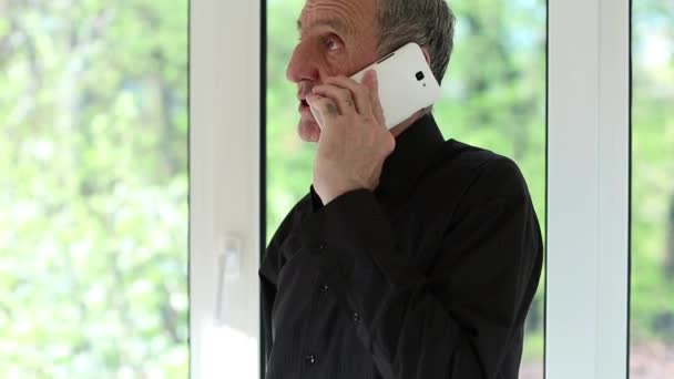 Man talar i en mobiltelefon med ett allvarligt ansikte — Stockvideo