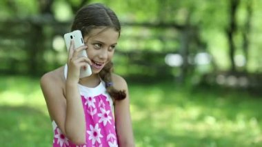 Güzel kız çimenlerin üzerinde oturur ve cep telefonuyla konuşuyor