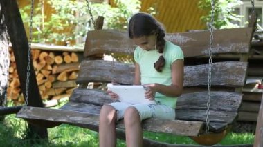 Tablet bilgisayar ile güzel kız salıncak bankta oturur