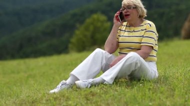 Çim ve smartphone kullanarak üzerinde kadın oturur