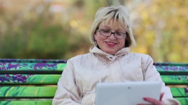 Kadın bankta oturur ve tablet Pc iletişim kurar