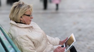 Kadın bankta oturur ve kullanır tablet bilgisayara