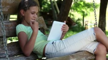 Tablet bilgisayar ile güzel kız salıncak bankta oturur