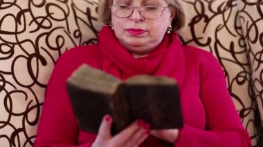 Kadın kıdemli bir divan ve okuma antik kitap üzerinde oturur