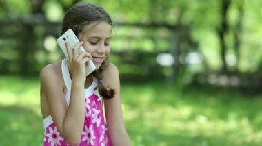 Kız çimenlerin üzerinde oturur ve telefonla konuşuyor