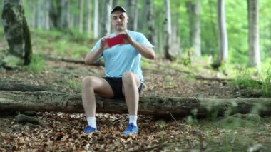adam düşmüş bir ağaç üzerinde oturur ve fotoğraf yapar