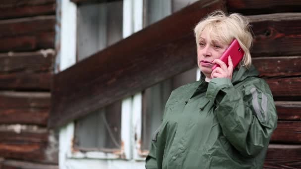 Woman in green raincoat talks on cell phone — Stock Video