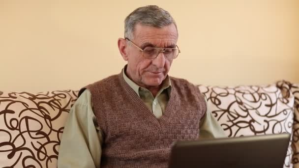 Hombre mayor escribe texto utilizando el ordenador portátil — Vídeo de stock