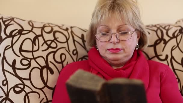 Blonde woman sits on a divan and reads ancient book — Stock Video